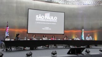 Foto da Célia Leão (Secretária de Estado dos Direitos da Pessoa com Deficiência de São Paulo) e dos convidados no palco do auditório da Secretaria.
