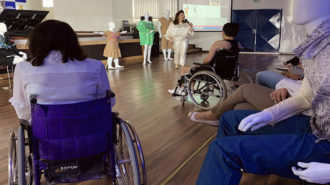 Foto da ministrante Andreia Miron, a Secretária Célia Leão e outra cadeirante de costas na aula aberta de moda inclusiva.